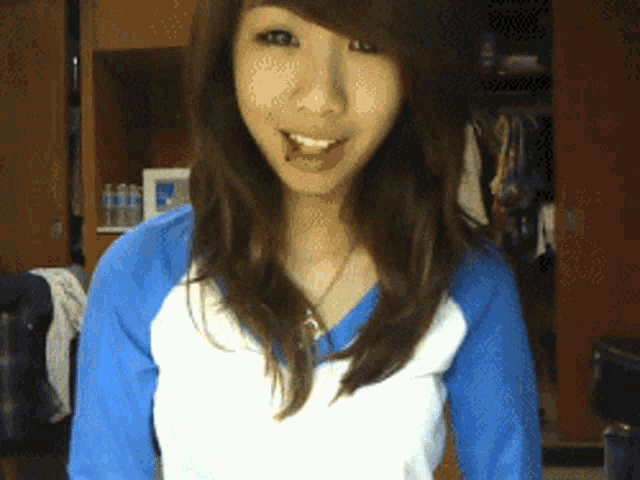 a girl in a blue and white shirt smiles for the camera