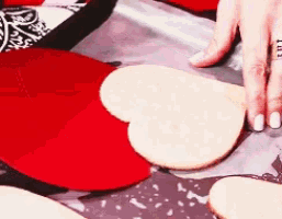 a person with white nails is holding a heart shaped piece of paper