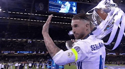 a soccer player is holding a trophy and giving a high five .