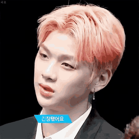 a young man with pink hair is wearing a suit and earrings