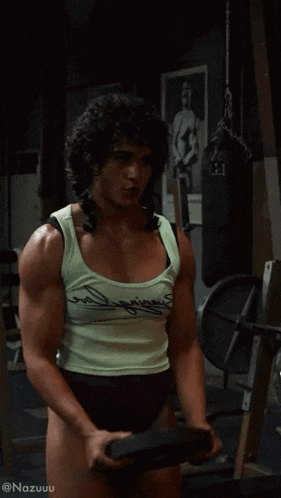 a woman in a tank top is holding a barbell in a gym with the hashtag nazuuu