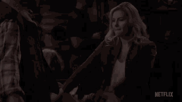 a woman is sitting in a chair with her mouth open and a man is shaking her hand .