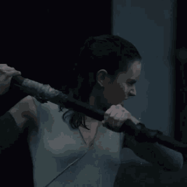 a woman is holding a sword in her hands and looking at the camera .