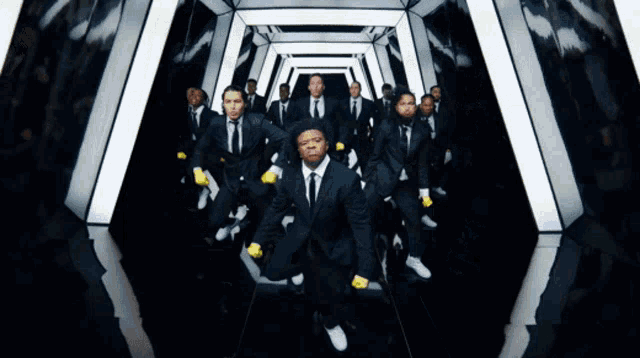 a group of men in suits are dancing in a dark room