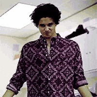 a man in a purple shirt is standing in a room with his arms outstretched and making a funny face .