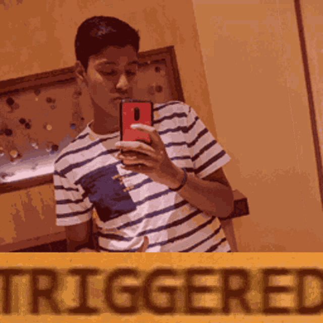 a young man takes a selfie in front of a yellow sign that says triggered