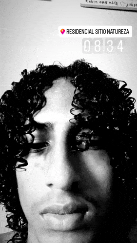 a black and white photo of a man with curly hair and a sign that says " residencial sitio natureza "