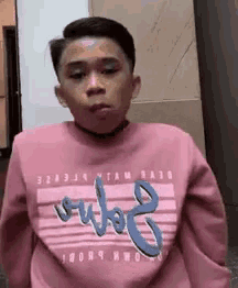 a young boy is wearing a pink sweatshirt with the word outo8 on the front .