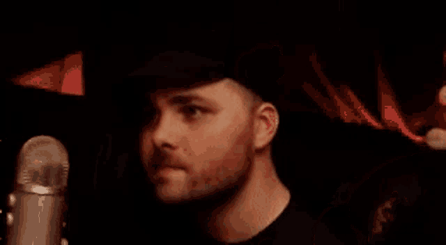 a man in a hat is standing in front of a microphone .