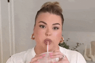 a woman wearing a white t-shirt and hoop earrings is making a funny face .
