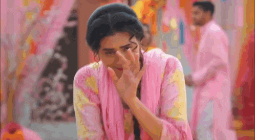 a woman in a pink dress is crying while a man in a pink robe stands behind her .