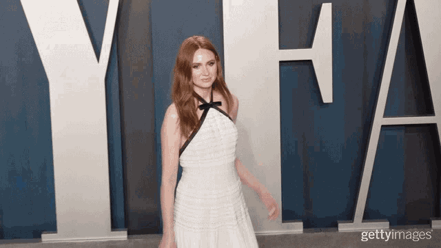 a woman in a white dress is standing in front of a sign that says yha