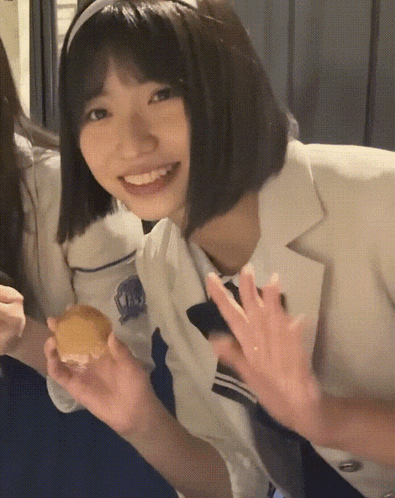 a girl wearing a headband holds a piece of food and smiles