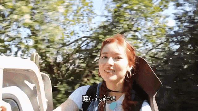 a woman with red hair is smiling and wearing a backpack with chinese writing on it