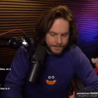 a man with long hair and a beard is giving an ok sign in front of a microphone .