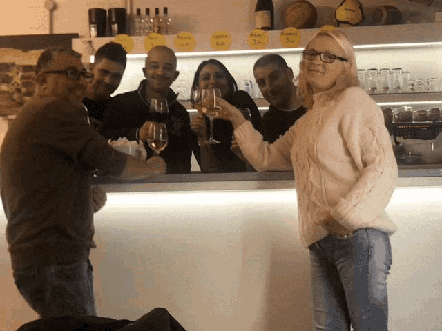 a group of people toasting with wine glasses in front of a bar with a sign that says " caffe " on it