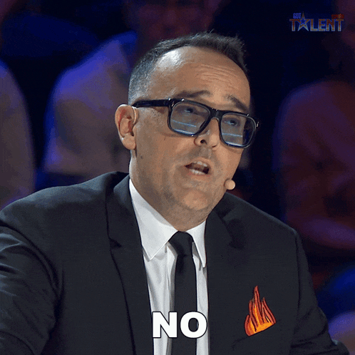 a man wearing glasses and a suit has the word no on his chest