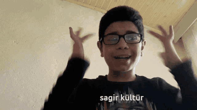 a young boy wearing glasses and a black shirt that says sagir kultur