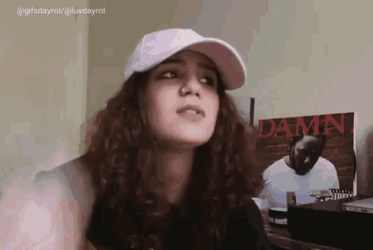 a woman wearing a white hat is standing in front of a damn album