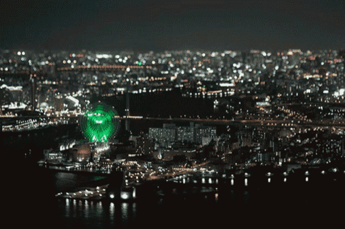 a green ferris wheel in the middle of a city