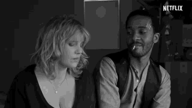 a man smoking a cigarette next to a woman with a netflix logo on the bottom