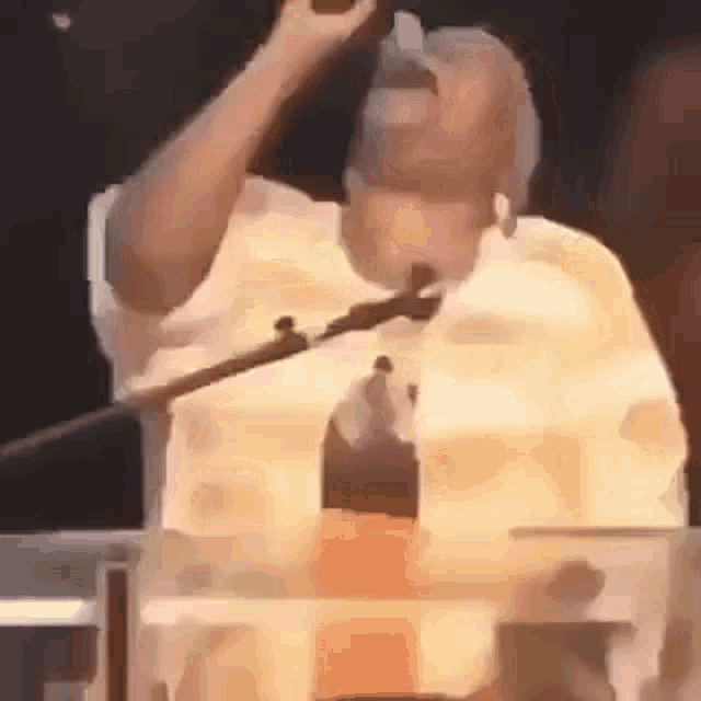 a man is standing at a podium holding a microphone and singing into it .
