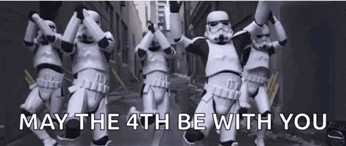 a group of stormtroopers are dancing on a street with the words `` may the 4th be with you '' above them .