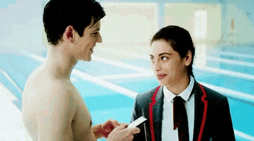 a shirtless man is giving a card to a girl
