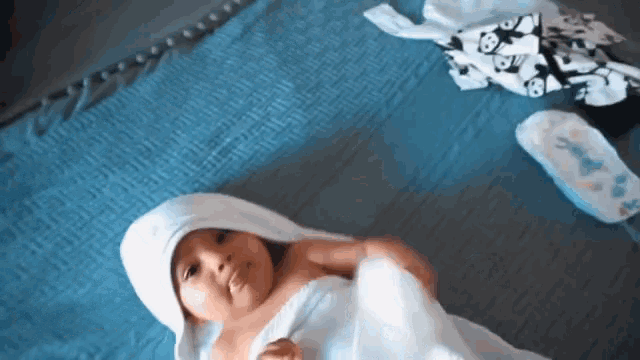 a baby wrapped in a white towel laying on a bed