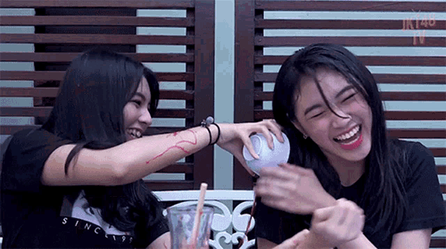 two girls are laughing and one of them has a tattoo on her arm that says since 1997