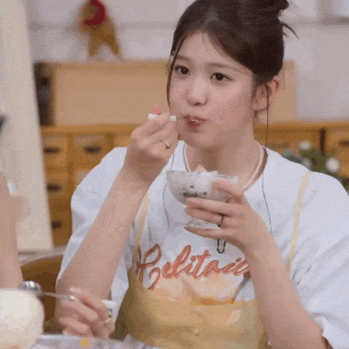 a woman wearing a white shirt with the word belitani on it is eating ice cream