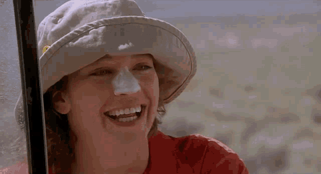 a woman wearing a hat and a red shirt smiles
