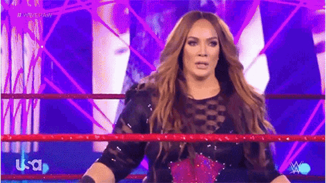 a woman is standing in a wrestling ring with a red rope .
