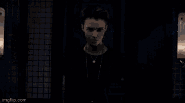a man is standing in a dark room with lamps .