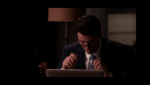 a man in a suit and tie is sitting in front of a laptop with the words bygones written below him