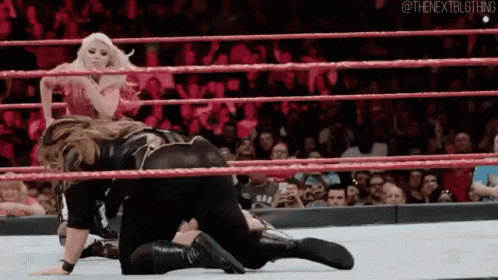 a woman is wrestling another woman in a wrestling ring while a crowd watches .