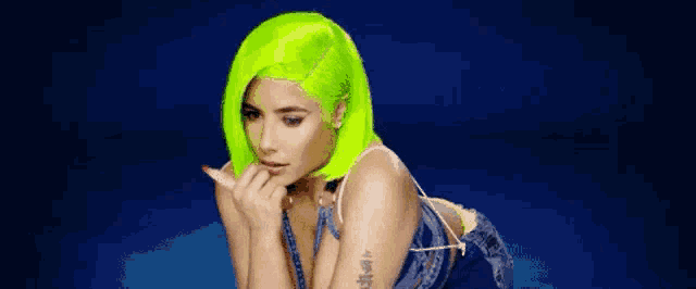a woman with neon green hair is wearing a blue dress and a blue background .