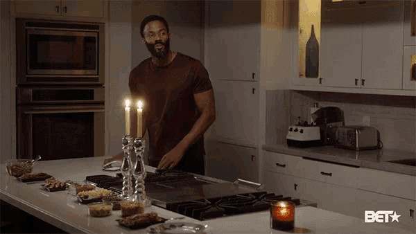 a man is standing in a kitchen with candles on the counter