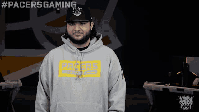 a man wearing a pacers hoodie stands in front of a sign that says #pacersgaming