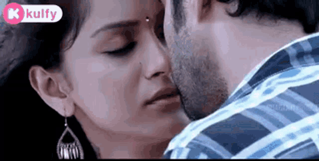 a man is kissing a woman on the cheek in a close up of their faces .