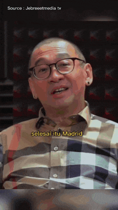 a man wearing glasses and a plaid shirt is talking about madrid