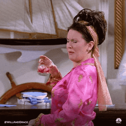 a woman in a pink robe is crying while holding a cup of tea .