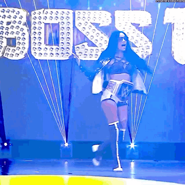 a woman stands on a stage in front of a sign that says ' rs ' on it