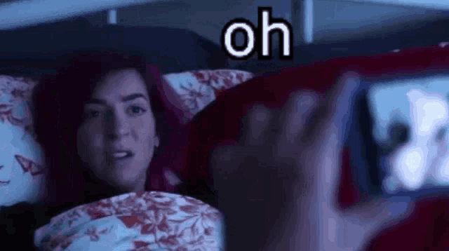 a woman is laying in bed taking a picture of herself with her cell phone .