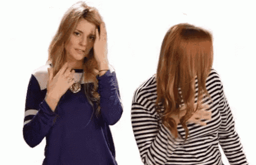 two women are standing next to each other and one of them is covering her face .
