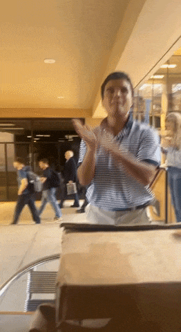 a man in a blue shirt is clapping his hands