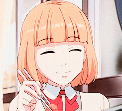 a girl with short orange hair is holding chopsticks and smiling