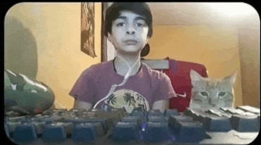 a young boy is sitting in front of a computer keyboard with a cat sitting next to him .