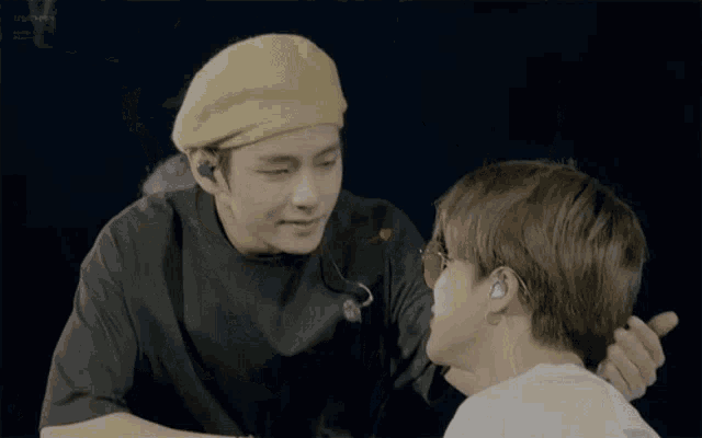 a man wearing a yellow beret is touching another man 's face .