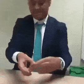 a man in a suit and tie is sitting at a table .